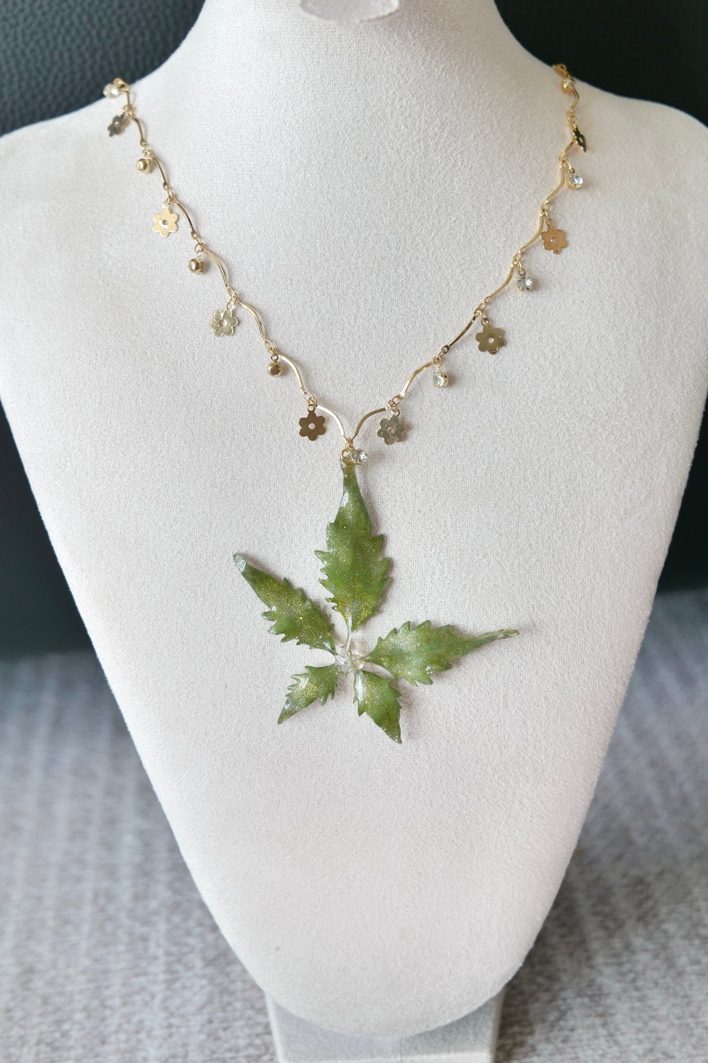 Side view of the serrated five-leaf floral-charm necklace by Terra Decode