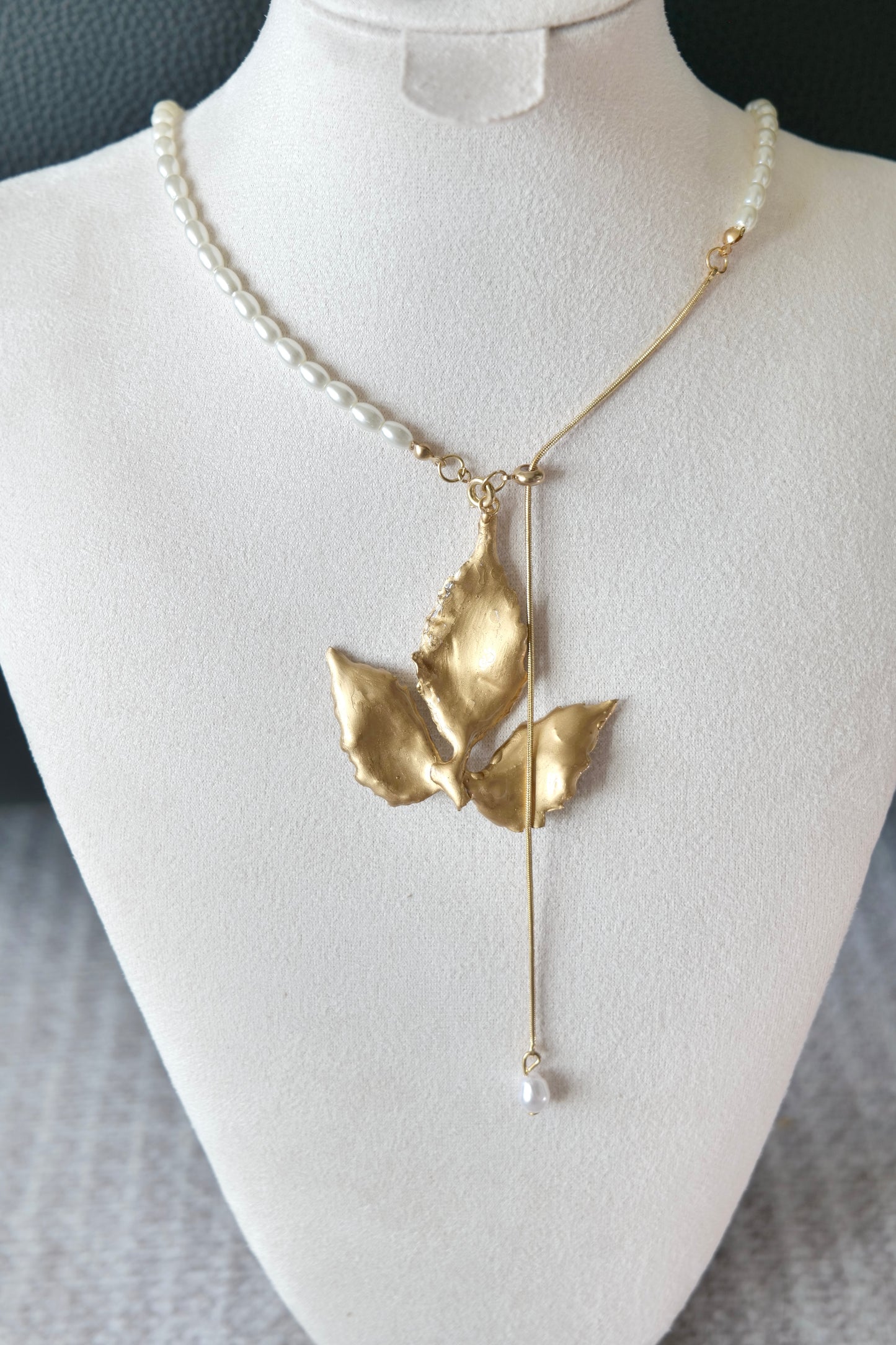 Single imitation-pearl drop below the gold-edged Boston ivy pendant
