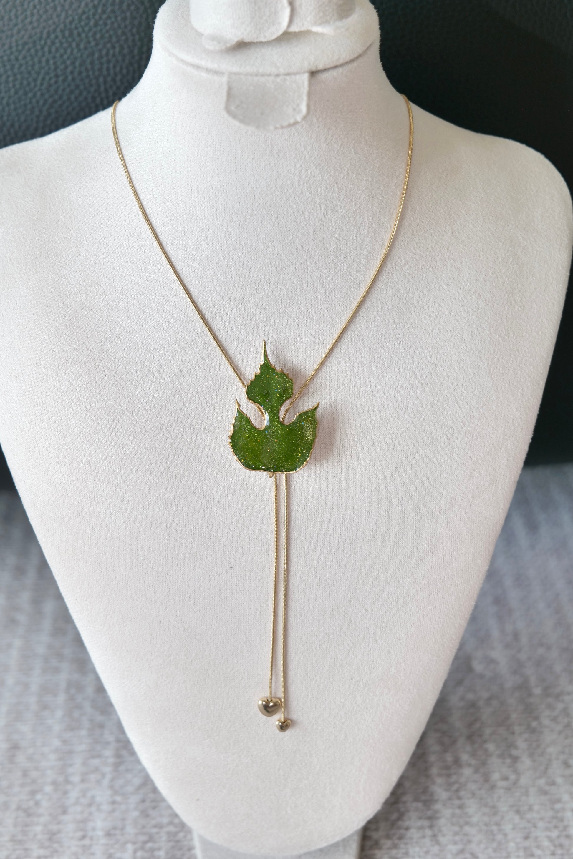 Left angled view of the sculptural green leaf double-heart lariat necklace by Terra Decode