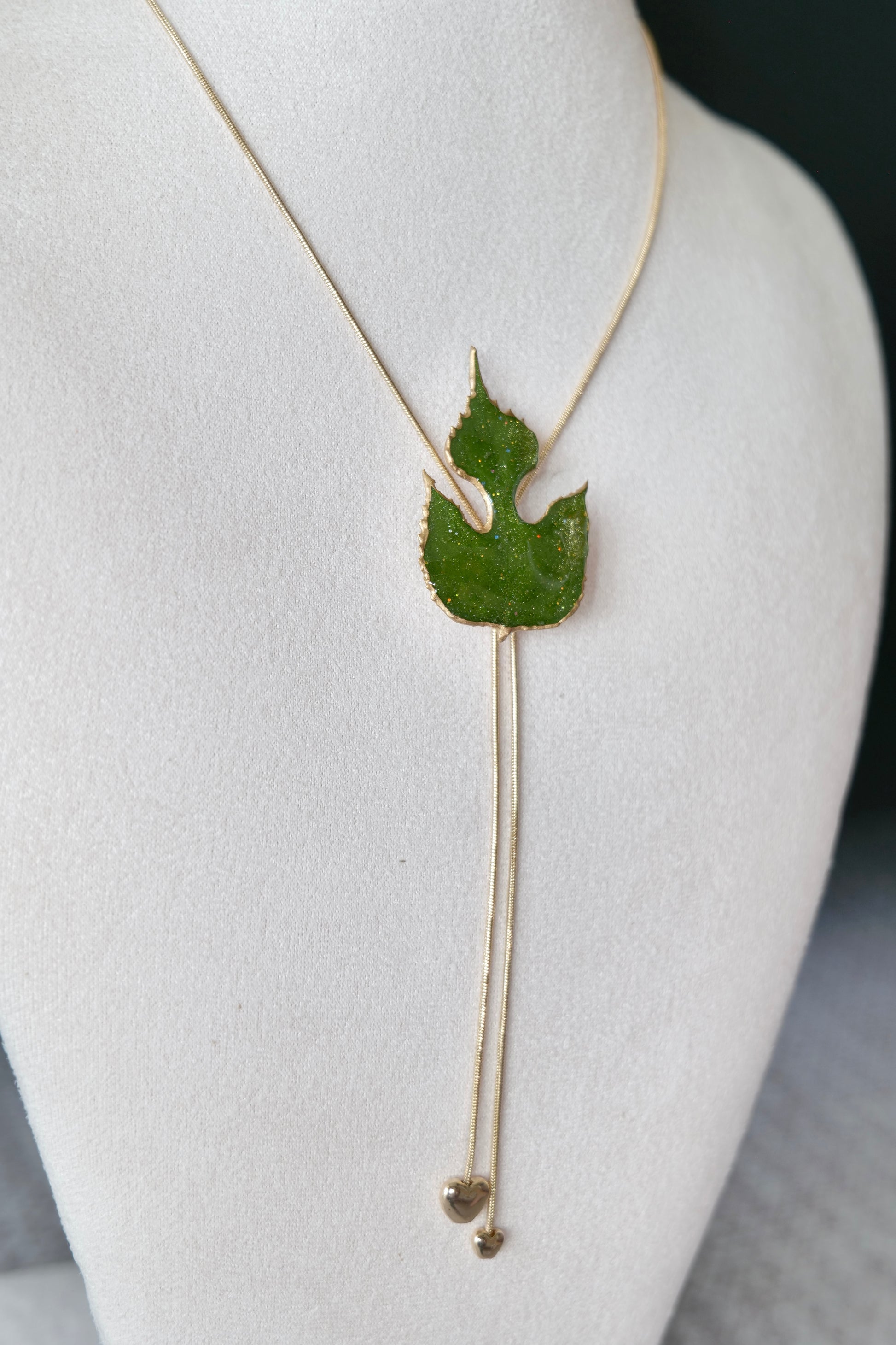 Right angled view of the sculptural green leaf double-heart lariat necklace by Terra Decode