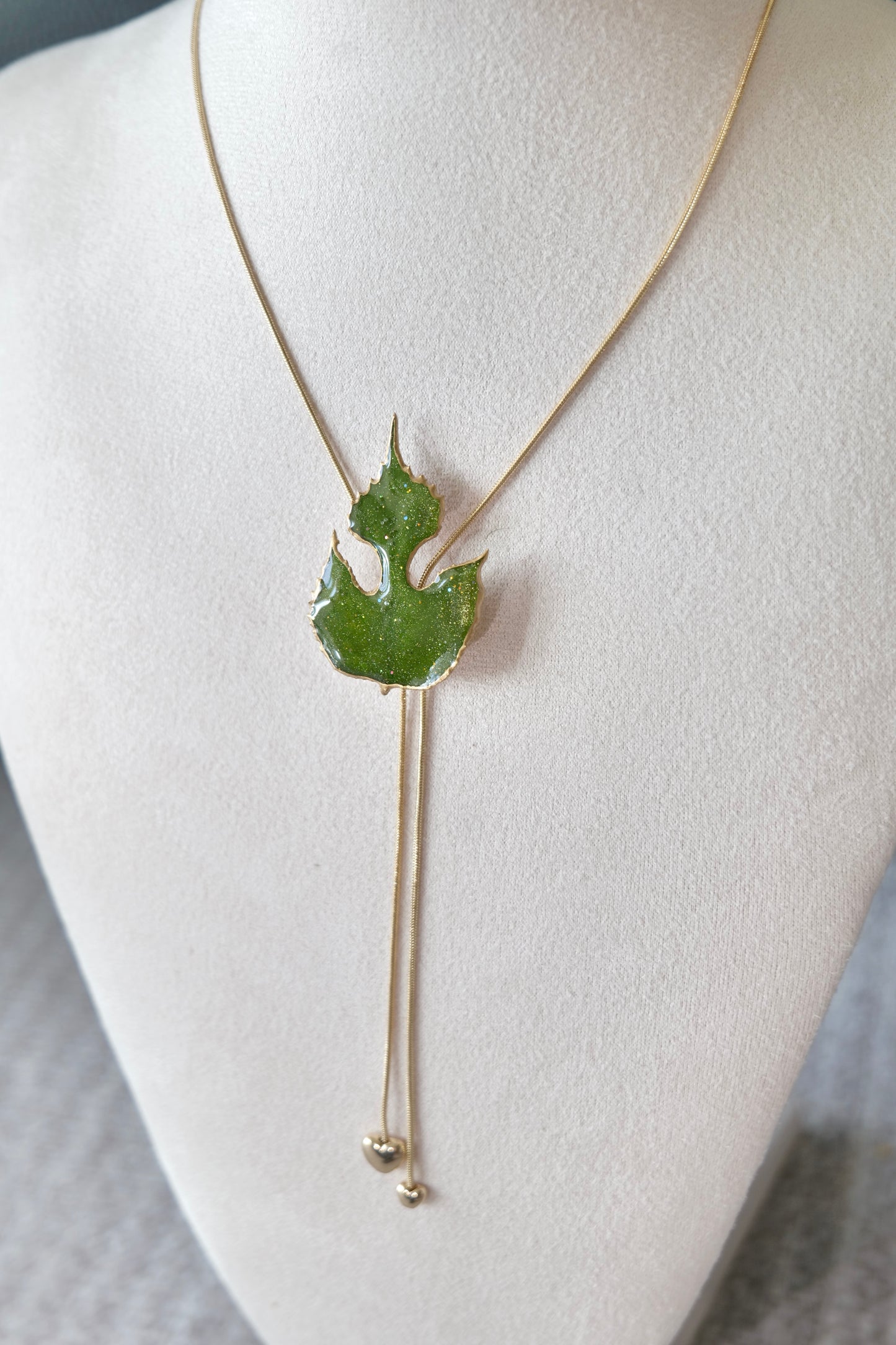 Two slender gold-toned hanging chains below the paper mulberry pendant