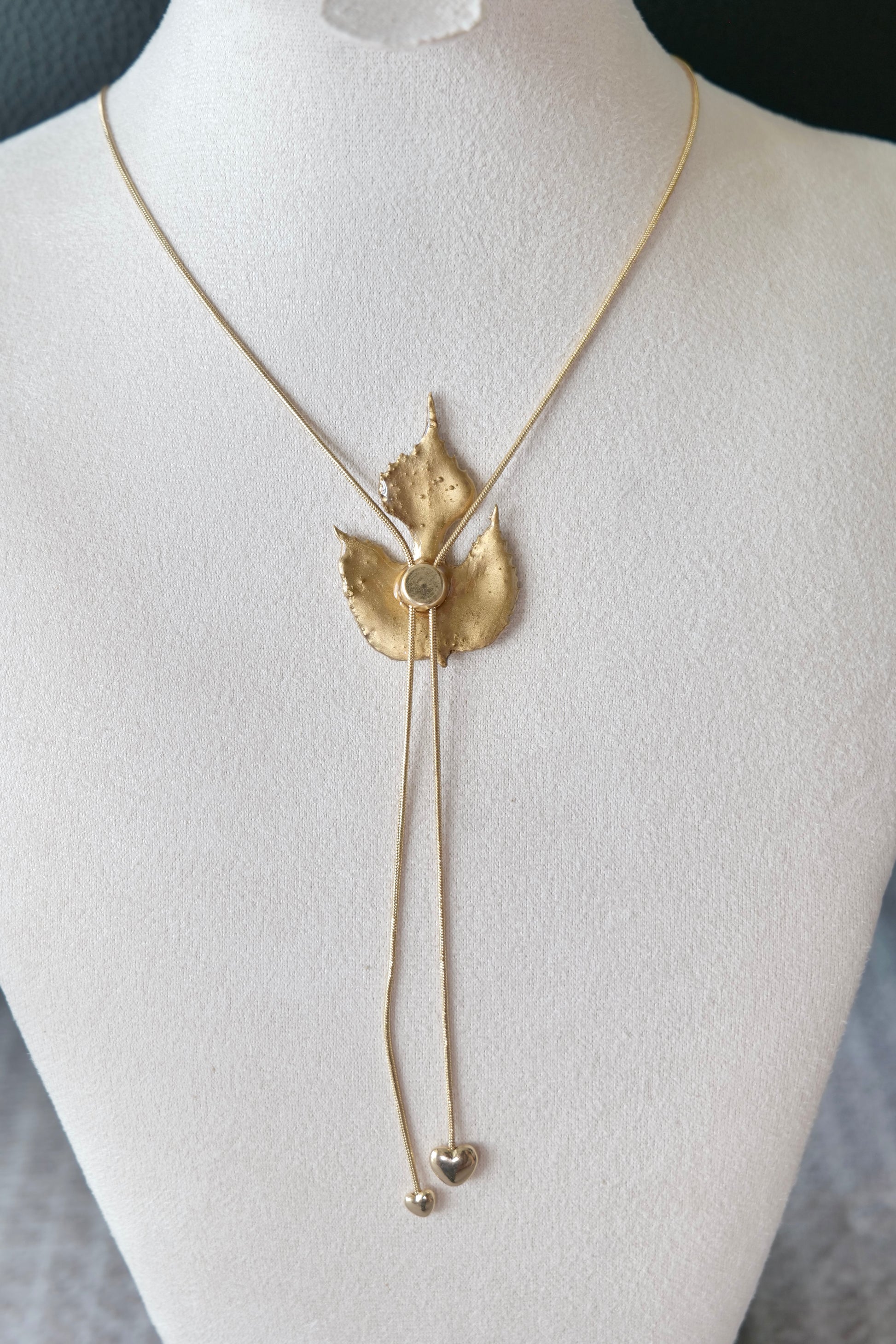 Side view of the sculptural green leaf double-heart lariat necklace by Terra Decode
