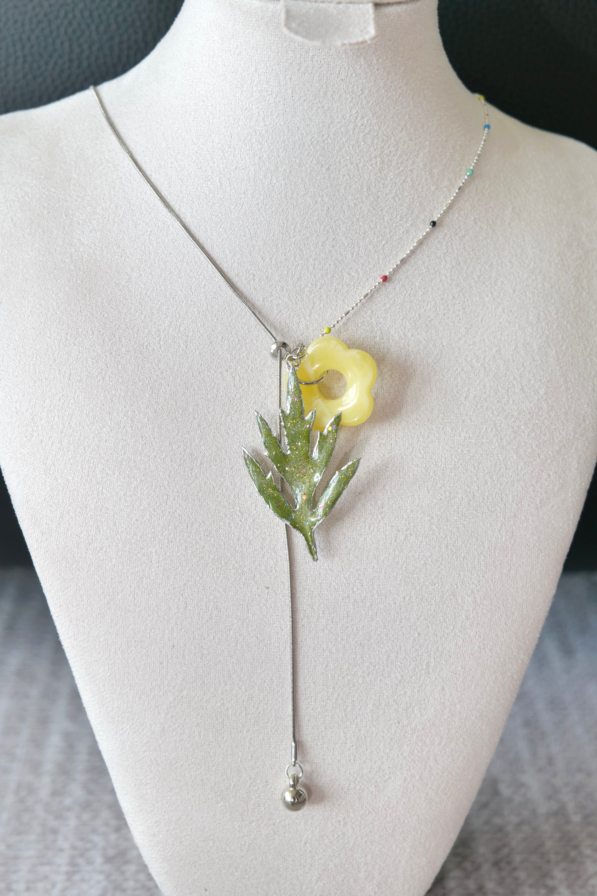 Angled view of the Chinese mugwort pendant and silver-toned mixed chain