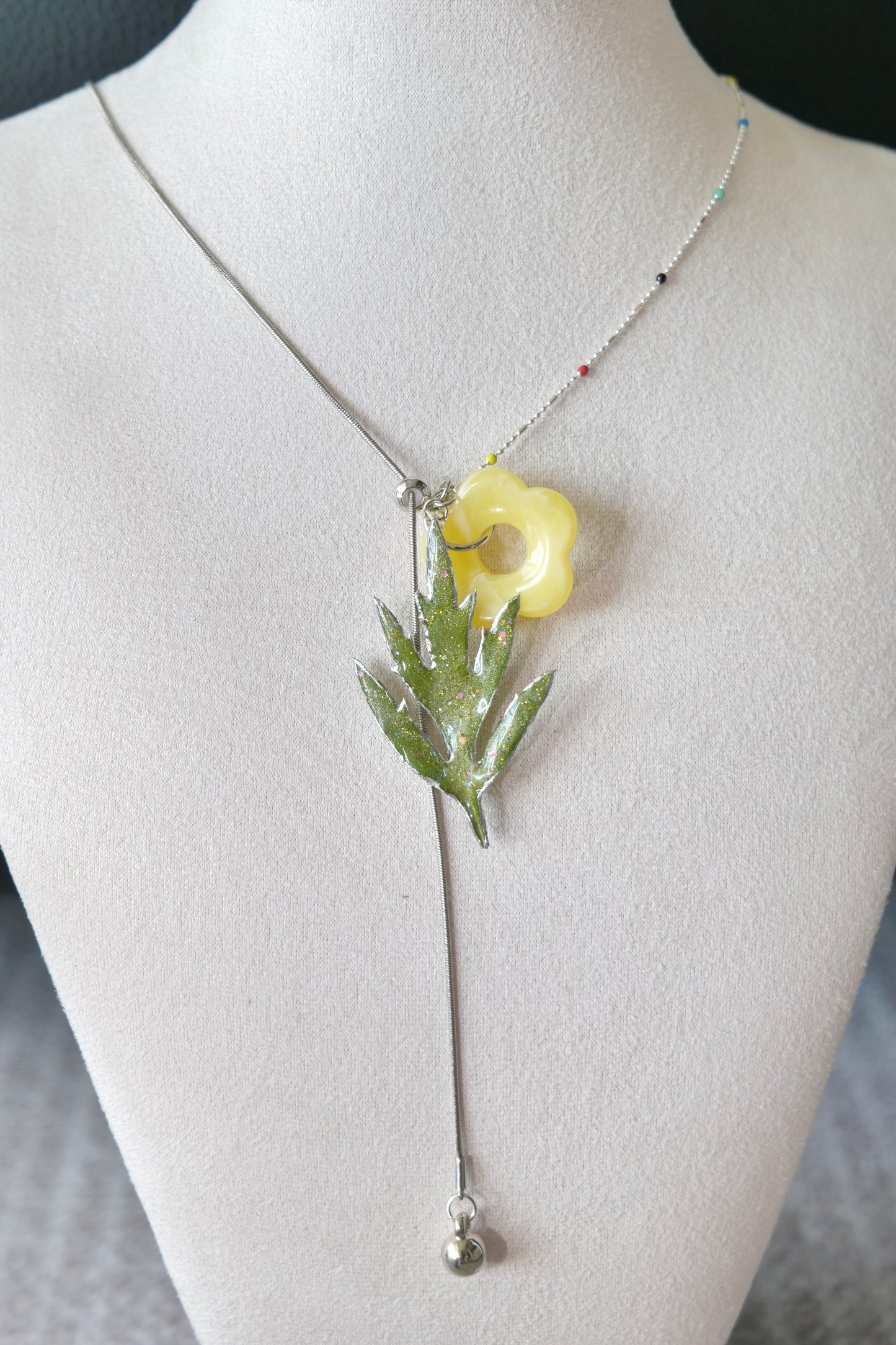 Angled view of coloured beads, Chinese mugwort and yellow acrylic flower charm