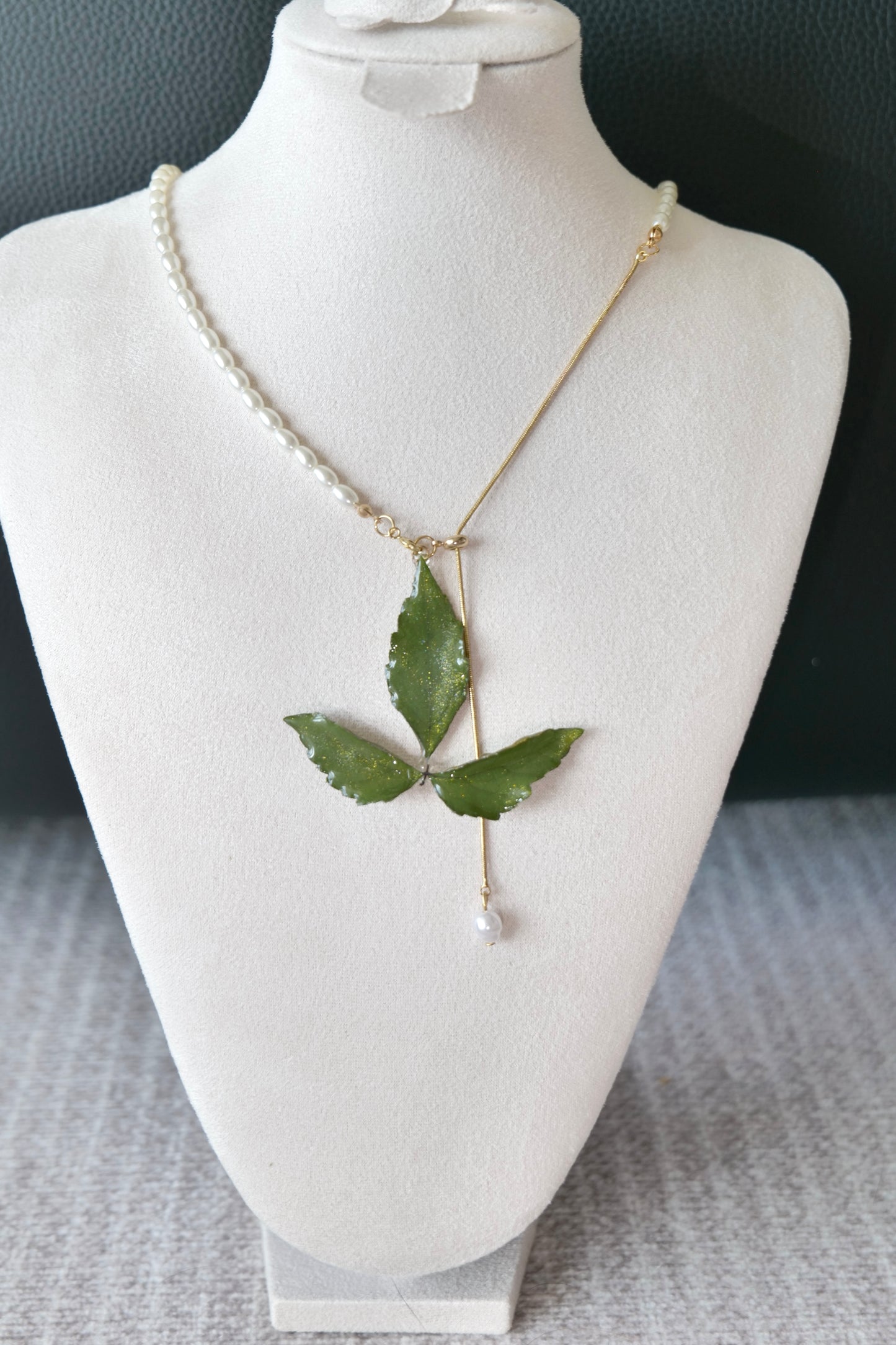 Right angled view of the minimal olive three-leaf pearl-drop necklace by Terra Decode