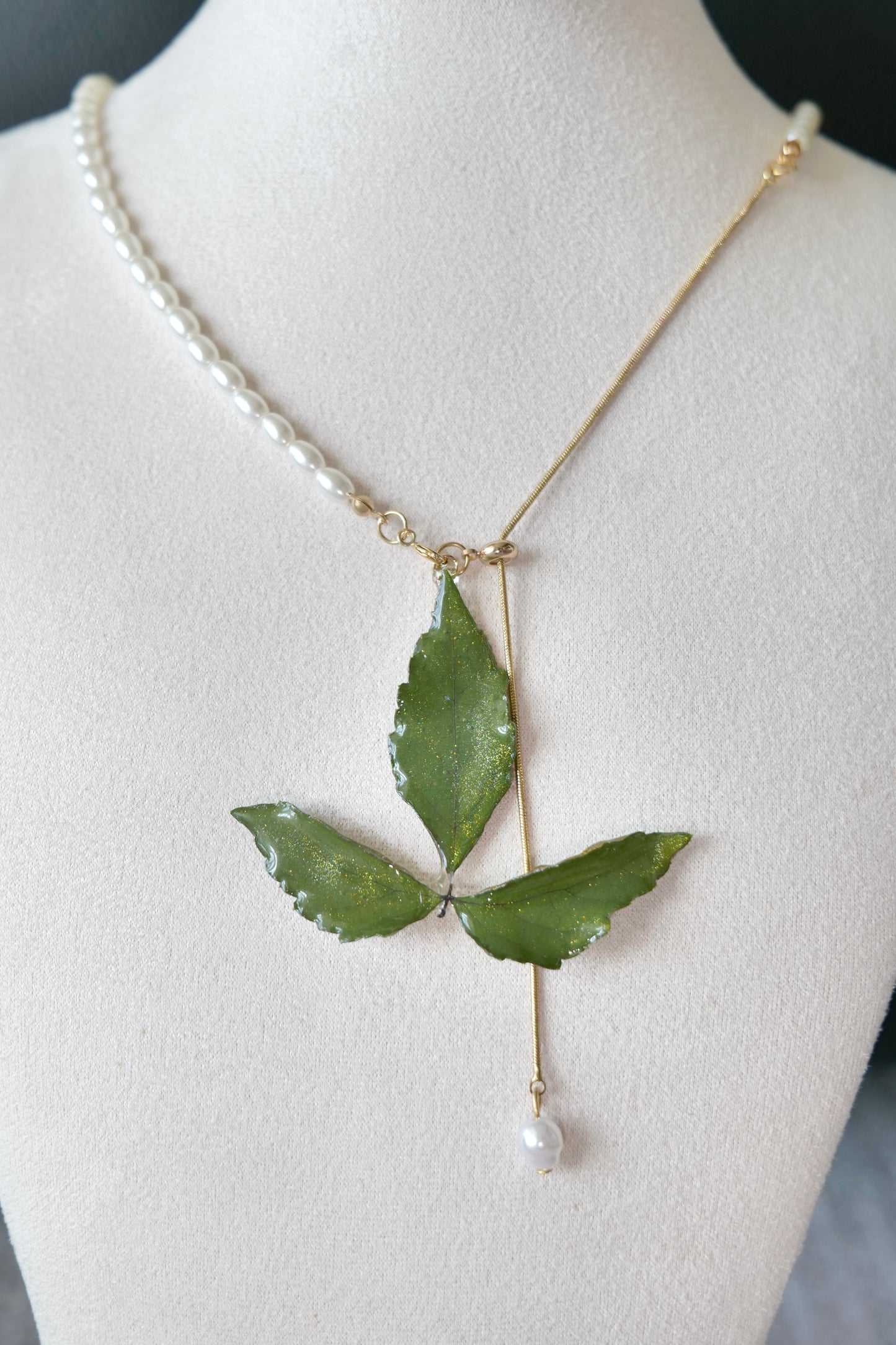 Side view of the minimal olive three-leaf pearl-drop necklace by Terra Decode