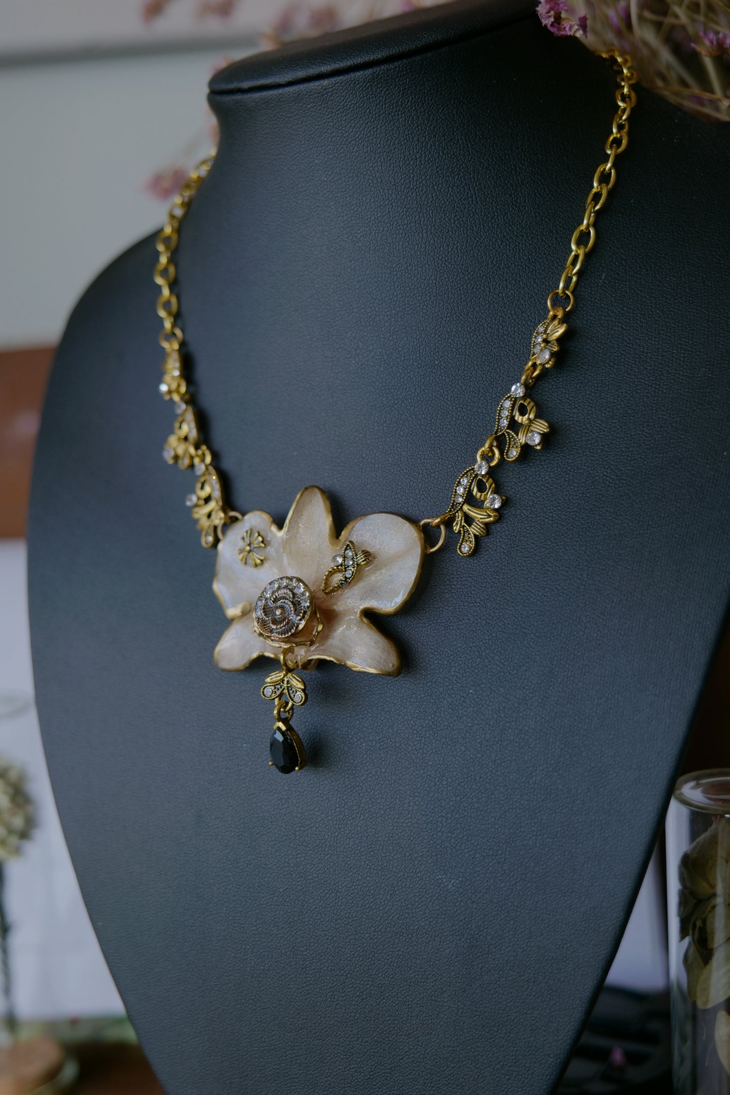 Antique-gold bee link and crystal details on the white Dendrobium necklace
