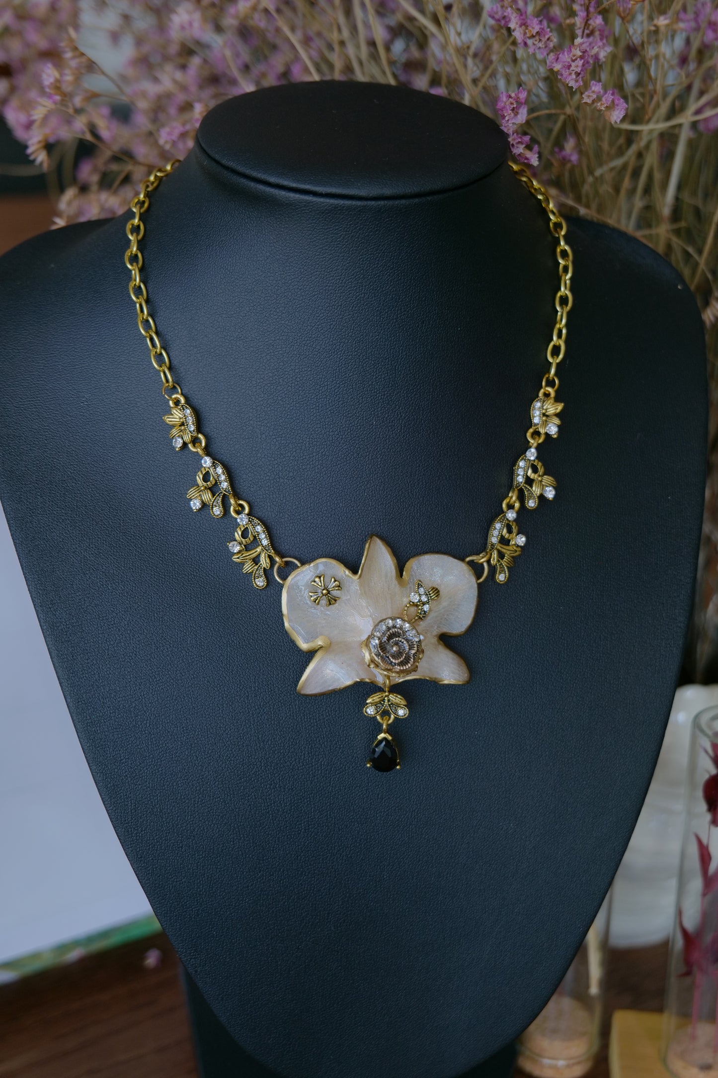 Close-up of black teardrop and crystal accents beneath the white Dendrobium orchid
