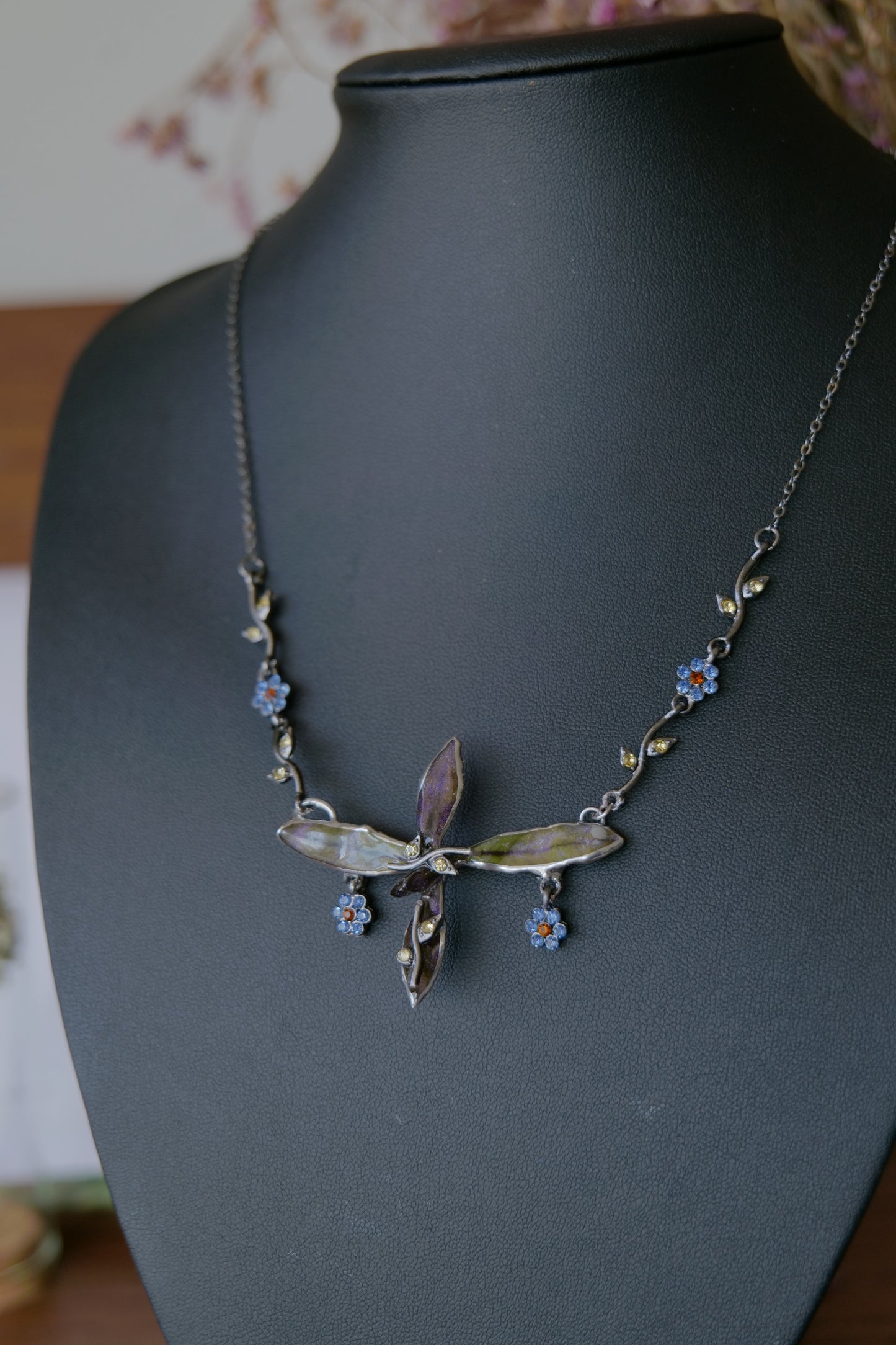 Styled view of dainty preserved leaf necklace with blue floral crystal charms