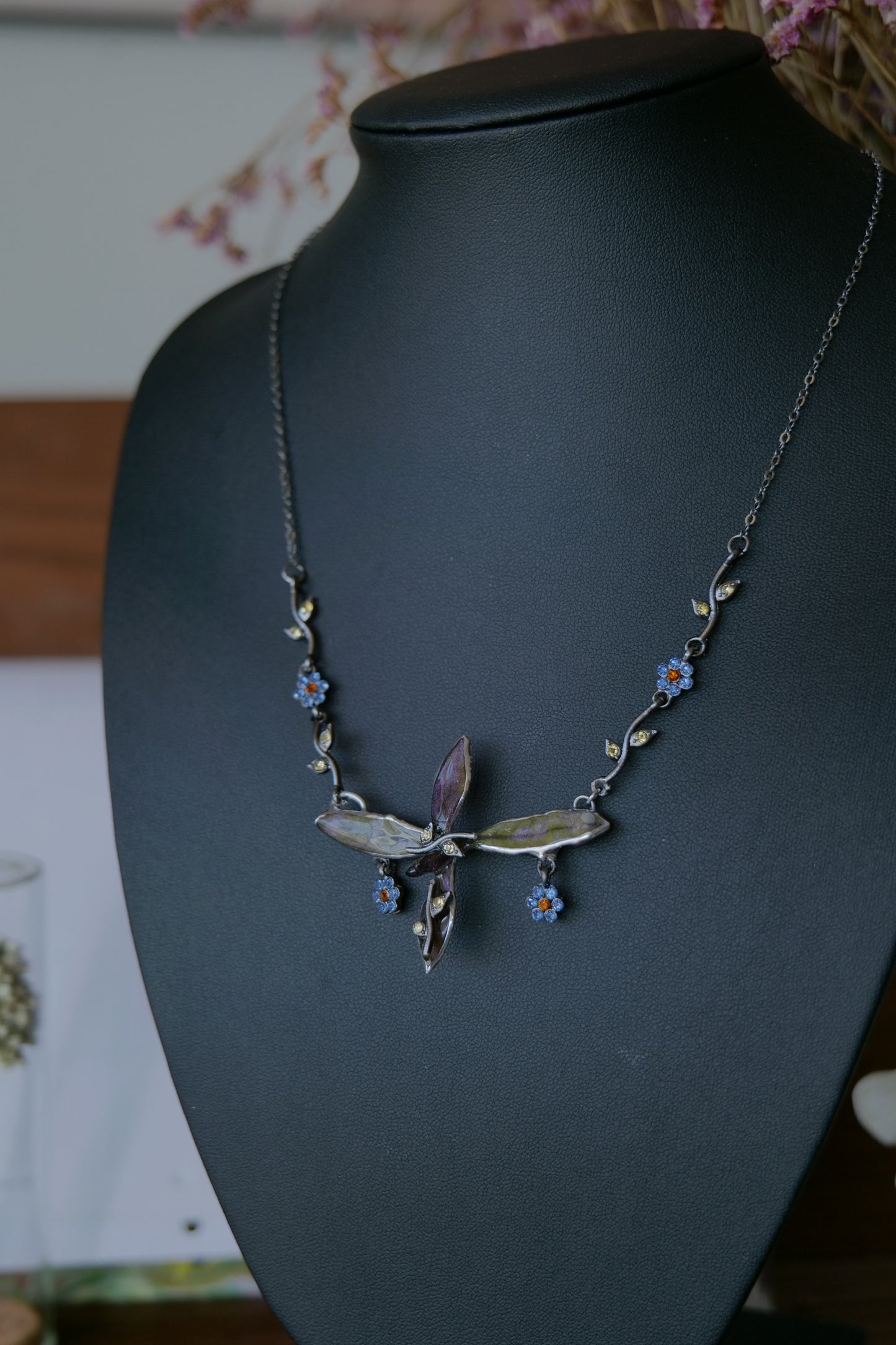 Fine gunmetal chain and blue floral crystal charm details on the Wild Whorl necklace