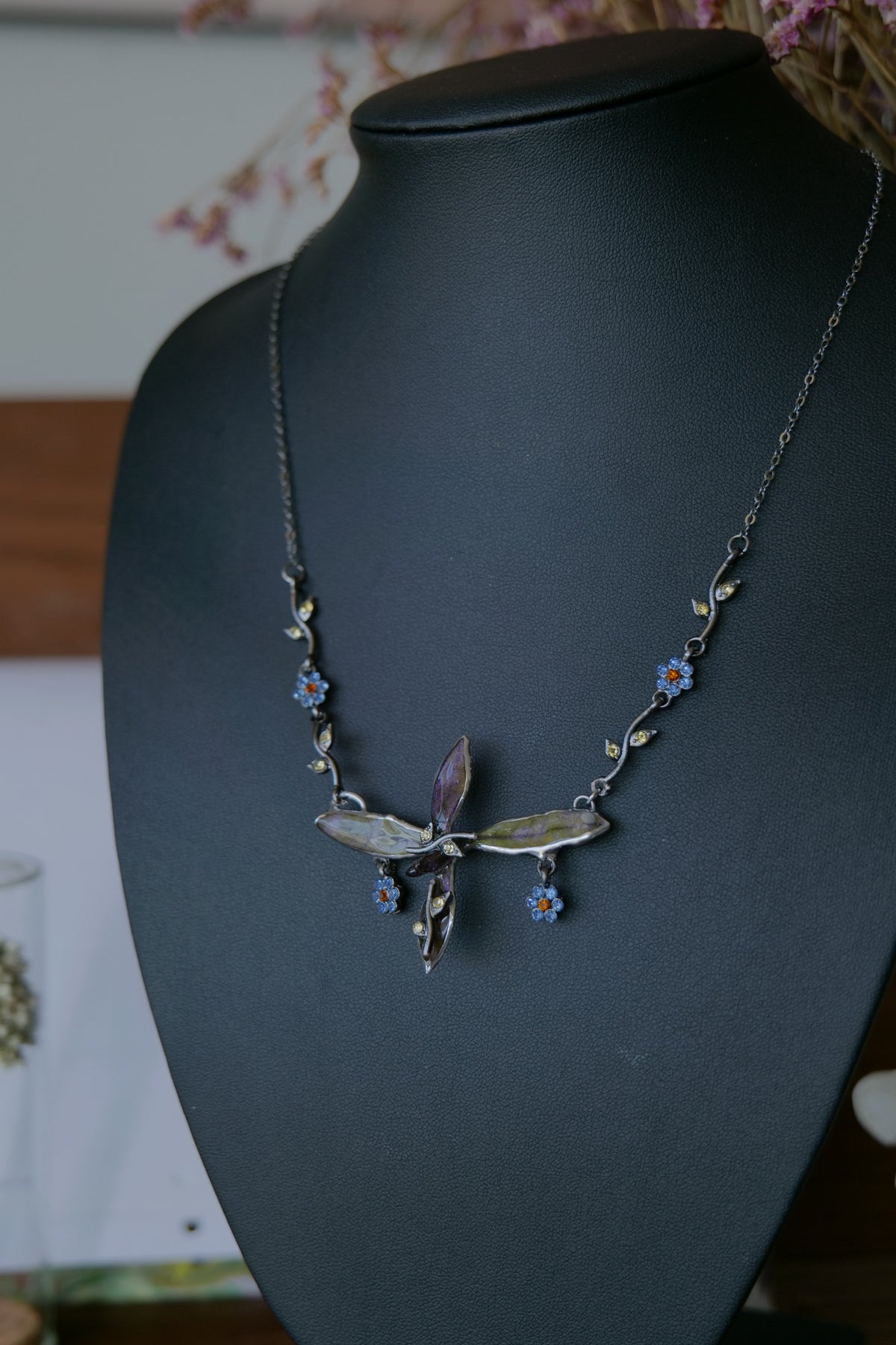 Fine gunmetal chain and blue floral crystal charm details on the Wild Whorl necklace