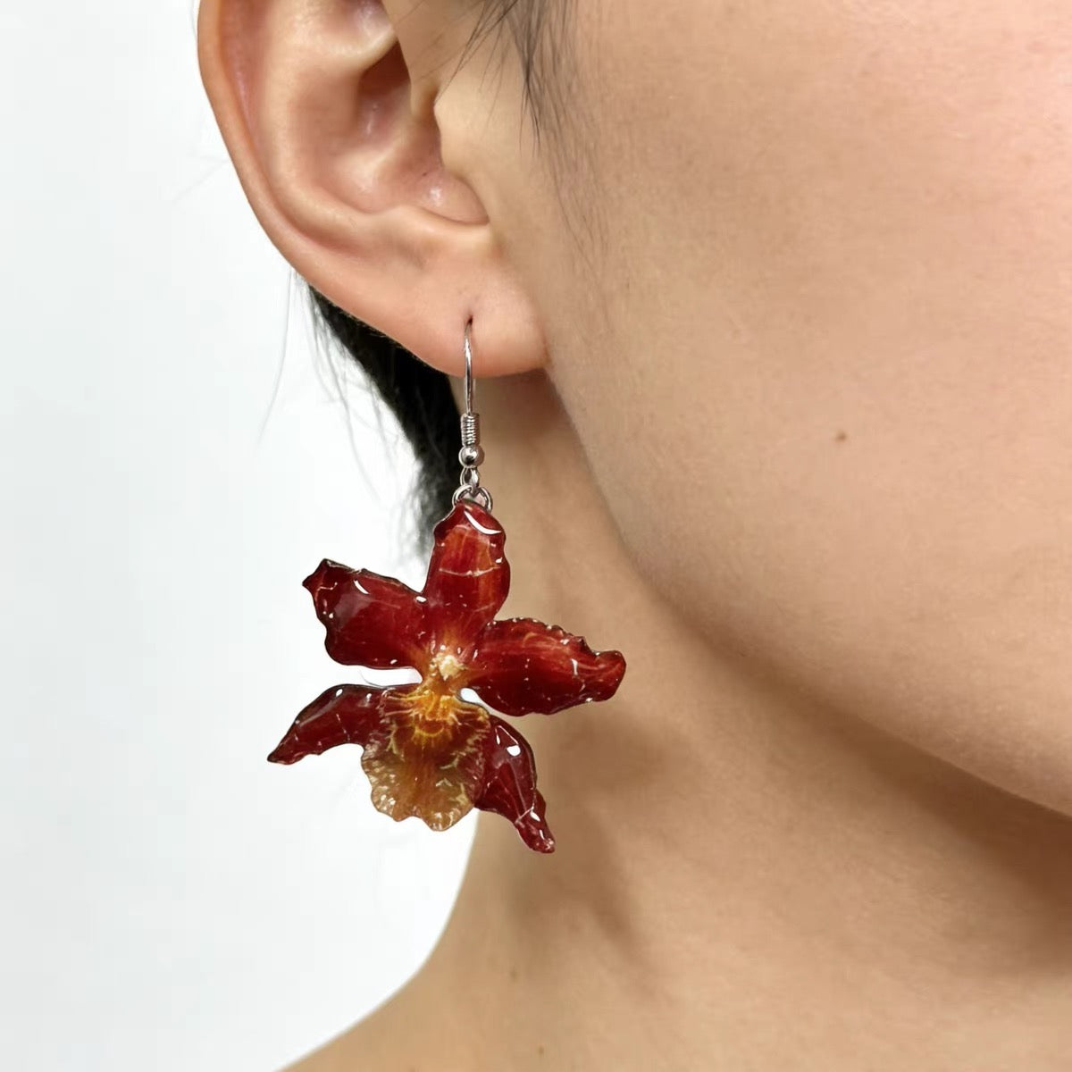 Crimson orchid earrings with resin petals worn on ear by Terra Decode