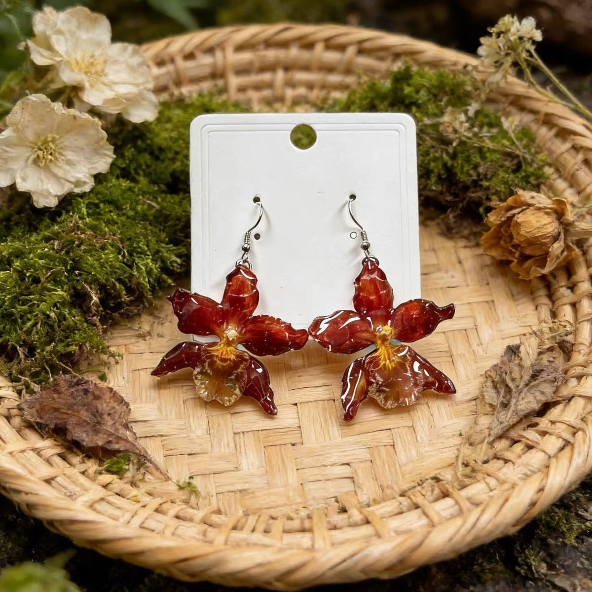 Crimson orchid earrings with resin petals in a botanical flatlay by Terra Decode