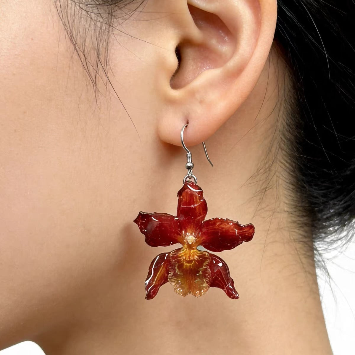 Crimson orchid drop earring with resin petals worn on ear by Terra Decode