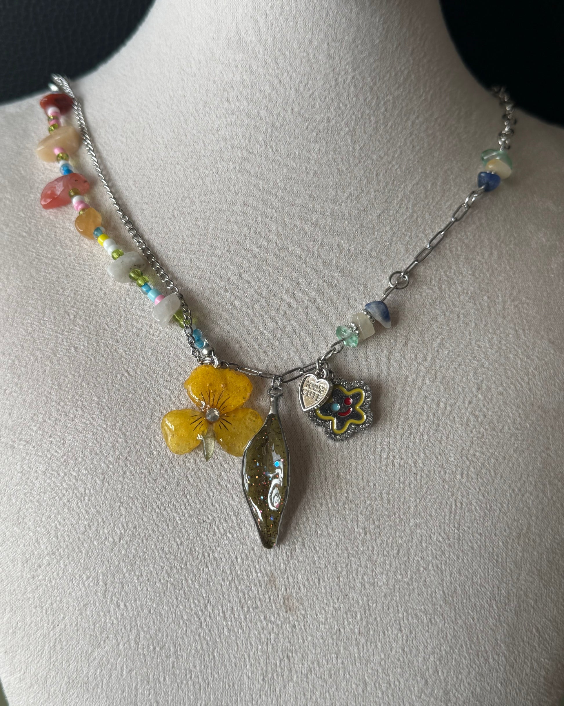 Yellow pansy and nandina leaf charm necklace with colourful beads shown from the front