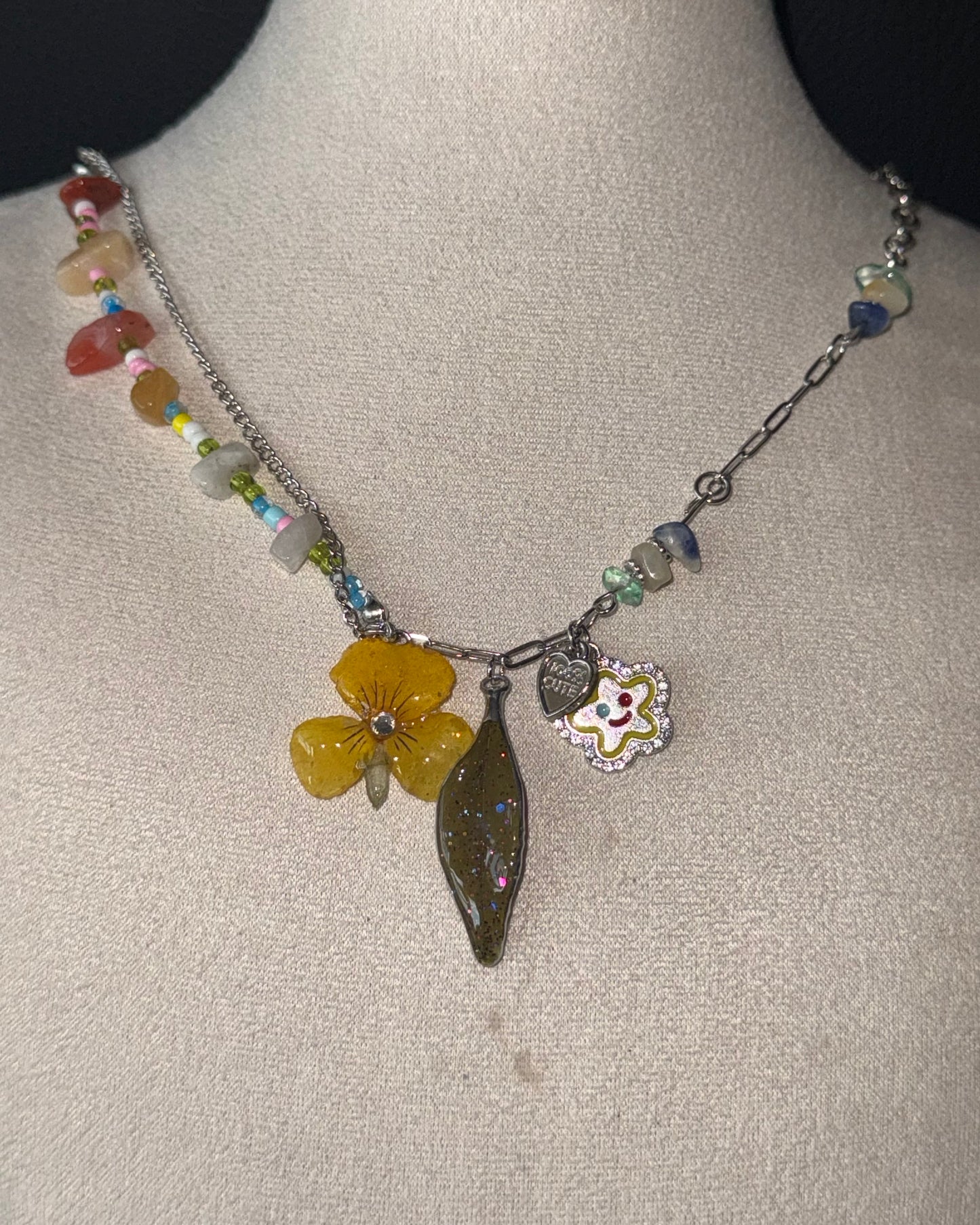 Reflective detail of yellow pansy, nandina leaf and playful flower charm