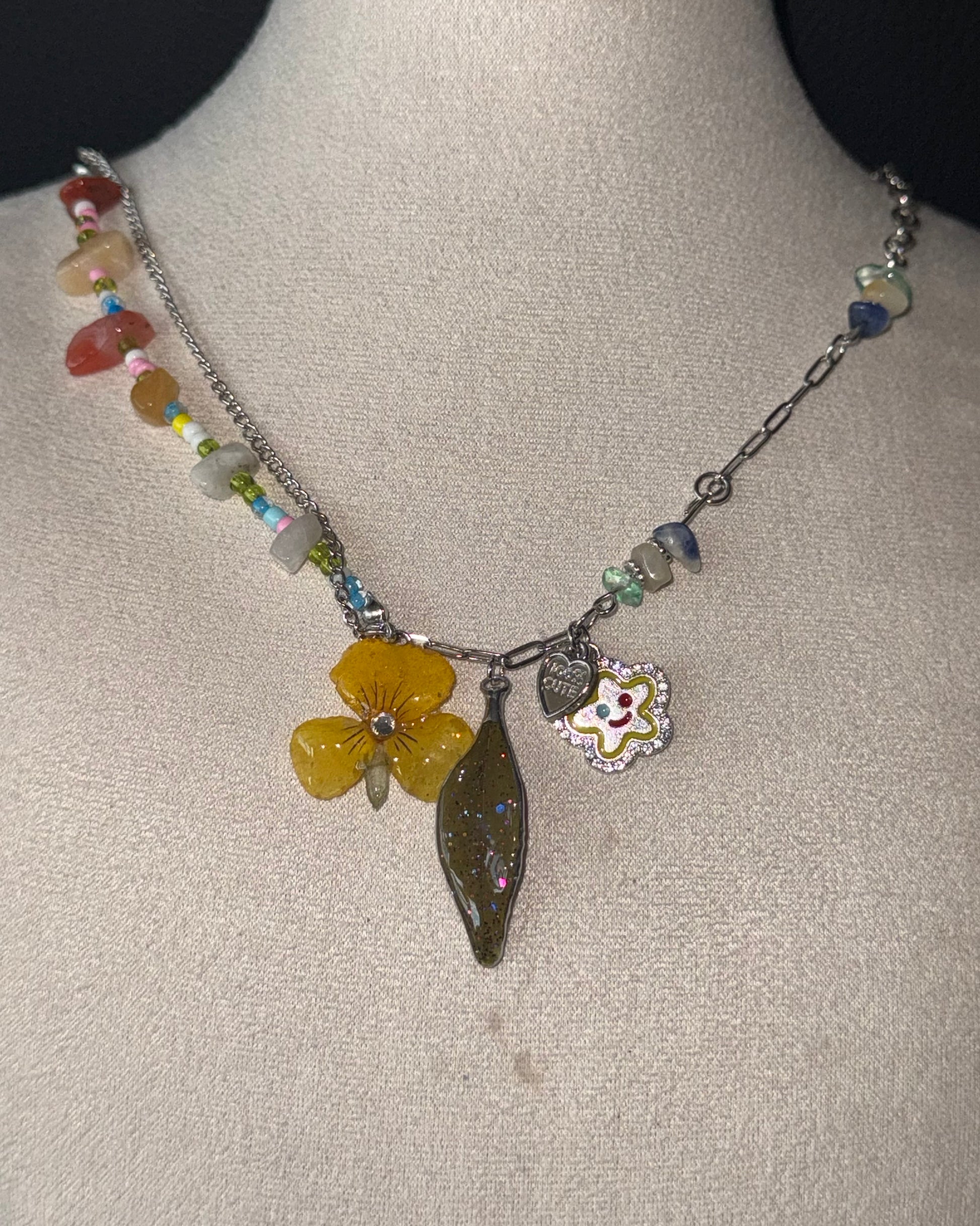 Reflective detail of yellow pansy, nandina leaf and playful flower charm
