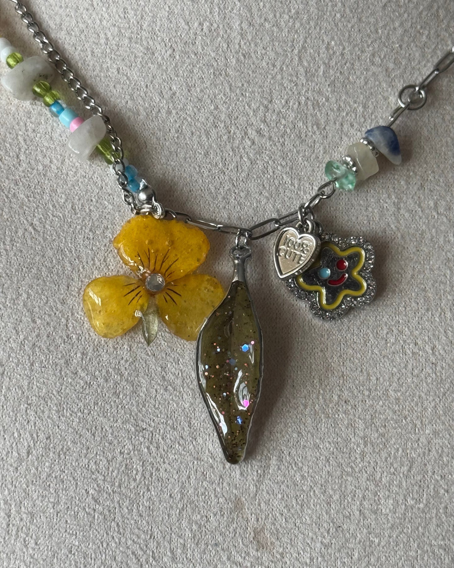 Close-up of yellow pansy, Nandina leaf, heart and smiling flower charms