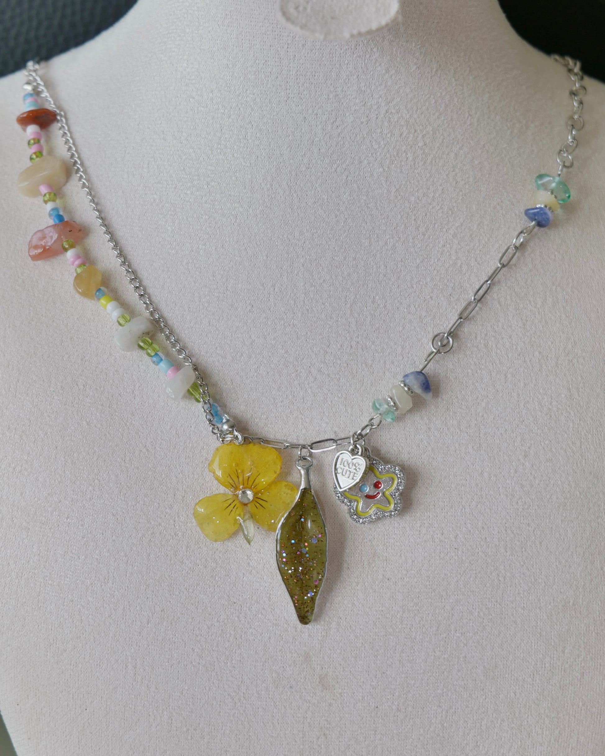 Natural-light front view of yellow pansy and preserved Nandina leaf necklace